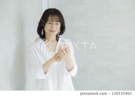 拿著智能手機的微笑的婦女 拿著智能手機的微笑的婦女 130535465