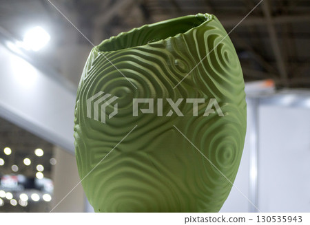Object printed on 3D printer close up. Model printed on 3D printer from molten plastic. Vase printed on 3D printer from molten plastic of green color. 3D printing technology. Additive FDM technologies Object printed on 3D printer close up. Model printed on 3D printer from molten plastic. Vase printed on 3D printer from molten plastic of green color. 3D printing technology. Additive FDM technologies 130535943