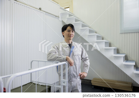 一名身穿工作服的男子在倉庫裡推著手推車 130536176