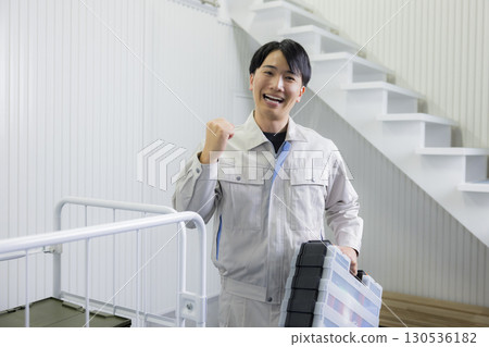 一名身穿工作服的男子推著推車 一名身穿工作服的男子推著推車 130536182