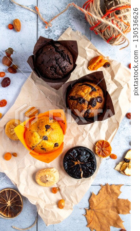 Assorted Muffins on Rustic Paper with Dried Fruits in Warm Light Studio Setting 130536626