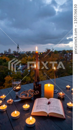 Illuminated Candles and Open Book on Wooden Tabletop with Cityscape View at Dusk 130536630