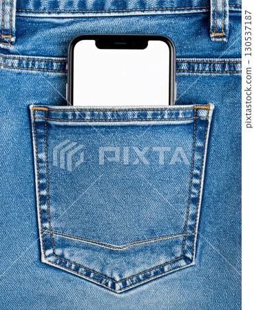 Smartphone with White Screen in the Back Pocket of Light Blue Denim Jeans Fabric 130537187