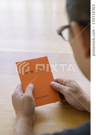 A man looking at his pension book 130538363