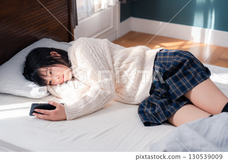 一名少女躺在床上使用智慧型手機 130539009