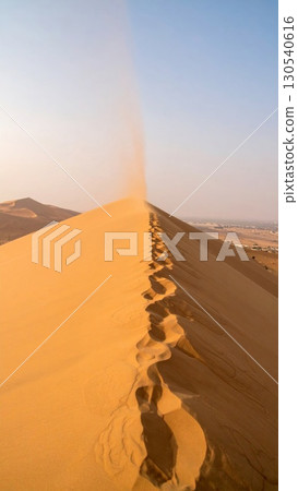 Desert Dune Ridge with Footprints in the Sand under Clear Blue Sky 130540616