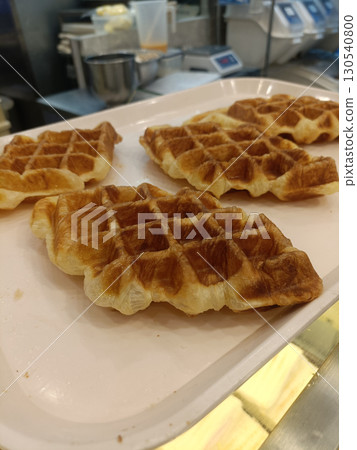 Golden waffle breakfast pastry bakery tray crisp texture flaky dough pastry shop plated pastry closeup food baked goods morning meal 130540800