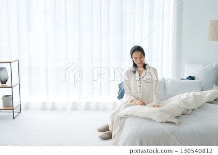 一位穿著睡衣的女士醒來並整理好她的被褥 130540812