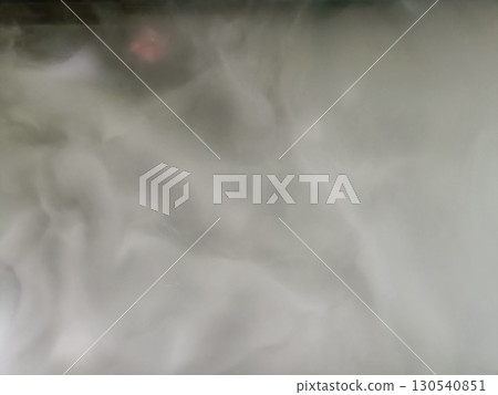 Thick white smoke rising, creating mysterious and foggy atmosphere, with hint of pink light in background, evoking sense of intrigue and calmness 130540851