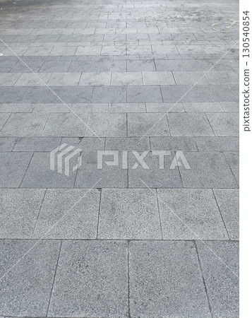 Paved stone walkway with rectangular gray stones arranged pattern, showing slight variations texture and color, creating clean and orderly surface 130540854