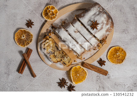 Slices of Traditional German Christmas stollen cake in background of handmade festive decor. Winter holiday treats. Vegan baking recipe Slices of Traditional German Christmas stollen cake in background of handmade festive decor. Winter holiday treats. Vegan baking recipe 130541232