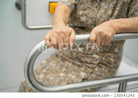 Asian elderly woman patient use toilet support rail in bathroom. 130541243