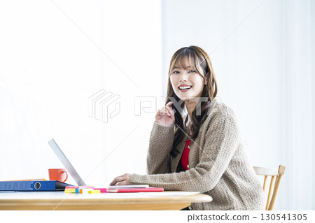 年輕女子使用筆記型電腦，看著相機，微笑 130541305