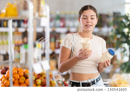 Girl hold bottle, choose and buy mayonnaise in store Girl hold bottle, choose and buy mayonnaise in store 130541605
