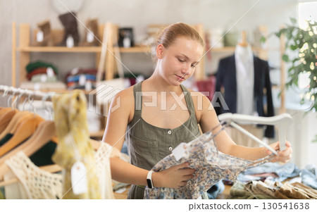 Teenage girl choosing something for summer in clothing store Teenage girl choosing something for summer in clothing store 130541638