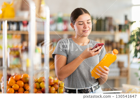 In shop youth girl scan QR code and take reading drink package bottle using phone camera In shop youth girl scan QR code and take reading drink package bottle using phone camera 130541647
