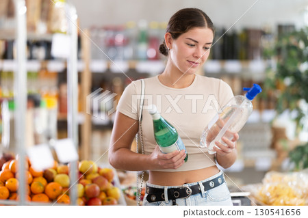 Girl hold bottles, choose and buy soda in store Girl hold bottles, choose and buy soda in store 130541656