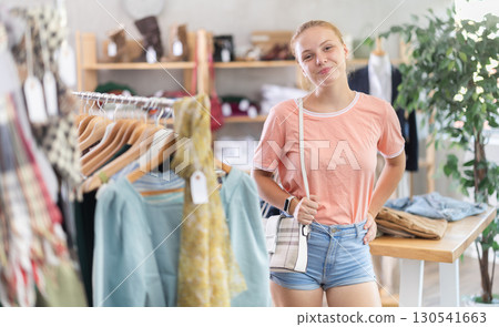 Young teen girl shopping - choosing a fashionable handbag in clothing store 130541663