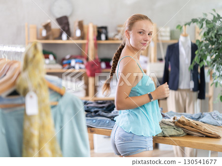 Woman standing in the store and choosing pants and shorts Woman standing in the store and choosing pants and shorts 130541677