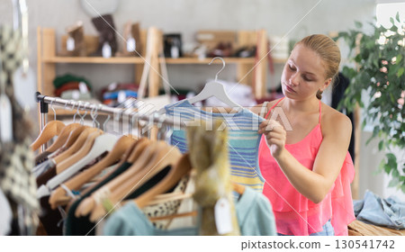 Joyful woman choosing tops in store 130541742