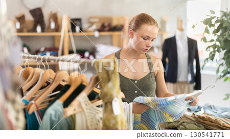 Joyful woman choosing tops in store 130541771