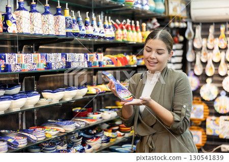 Happy female tourist looking to buy ornamental spoon rests at gift shop Happy female tourist looking to buy ornamental spoon rests at gift shop 130541839