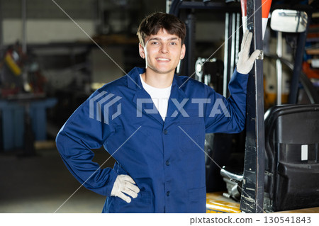 Young guy posing by forklift in workshop Young guy posing by forklift in workshop 130541843