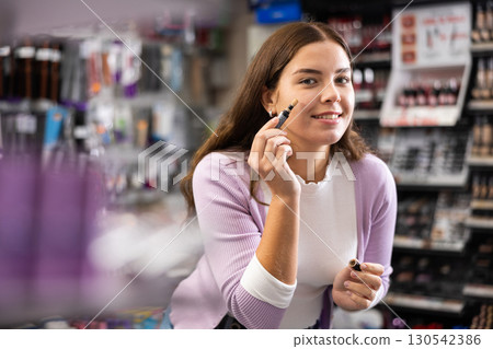 Young woman testing powder with brush in cosmetics store 130542386