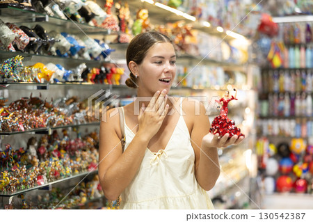Female buyer holds in hands tests figurine she-dancer flamenco in memorable gifts shop Female buyer holds in hands tests figurine she-dancer flamenco in memorable gifts shop 130542387