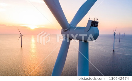Sustainable wind turbines generate renewable energy at sunset over 130542474