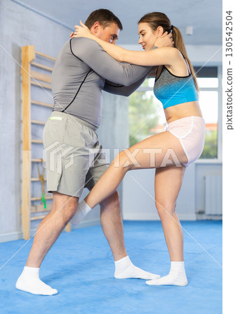 Young woman kicks attacking man - self-defense training in ring 130542504
