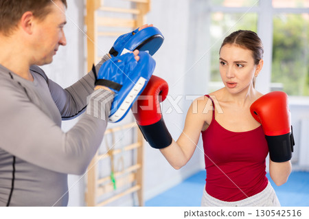 Adult man and young woman practicing boxing Adult man and young woman practicing boxing 130542516