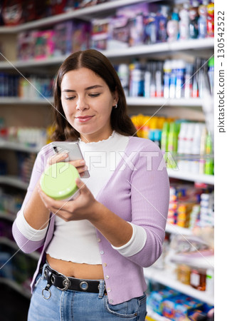 Female customer takes a photo using a mobile phone in cosmetics store Female customer takes a photo using a mobile phone in cosmetics store 130542522