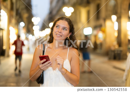 Young woman with phone in her hands walking down the street 130542558