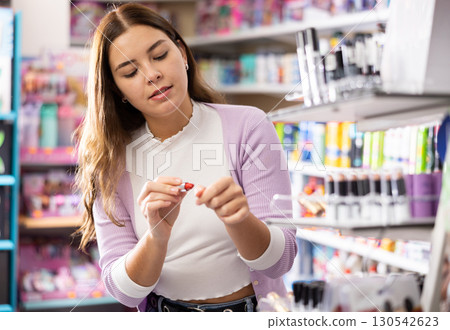 Girl buying lipstick or lip gloss in makeup store 130542623