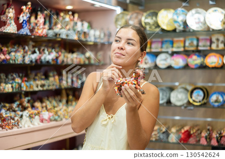 Barcelona souvenir shop - happy girl chooses bull figurine 130542624