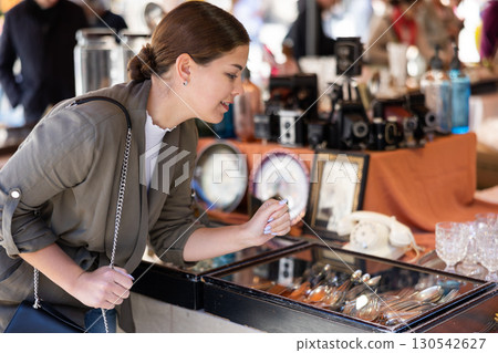 Happy female tourist looking to buy silverware at flea market 130542627