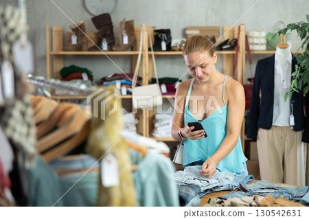 Young girl checking the quality of jeans or shorts using a steamer QR code on label Young girl checking the quality of jeans or shorts using a steamer QR code on label 130542631