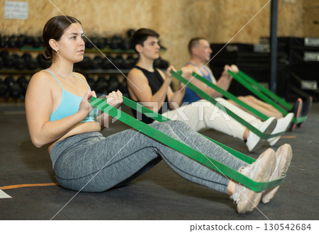 Focused young girl exercising with resistance band loop in gym 130542684
