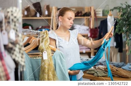 Teenage girl choosing something for summer in clothing store 130542722