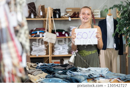 Teen girl holding discount sign in clothing store Teen girl holding discount sign in clothing store 130542727
