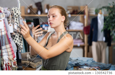Teenage girl scanning QR-code on scarf in clothing store Teenage girl scanning QR-code on scarf in clothing store 130542736
