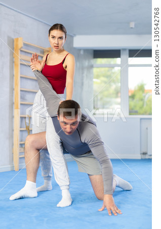 Young girl and middle-aged man practicing arm twist technique during self-defense courses 130542768
