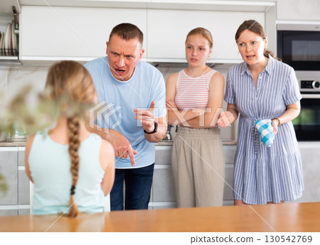 Displeased mother and father reprimanding preteen girl in home kitchen Displeased mother and father reprimanding preteen girl in home kitchen 130542769