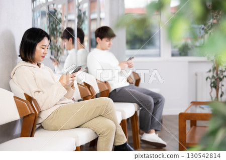 Young woman sitting in line with phone 130542814