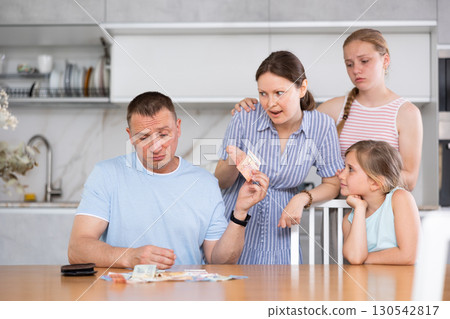 Dissatisfied husband and father give out pocket money to wife and children in kitchen 130542817