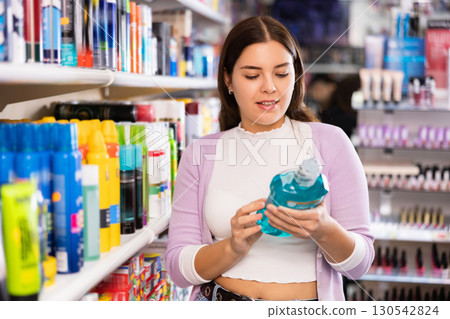 Young beautiful female shopper searching for mouthwashes Young beautiful female shopper searching for mouthwashes 130542824