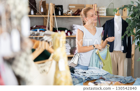 Positive joyful young teen girl looking for fashionable clothes in clothing boutique Positive joyful young teen girl looking for fashionable clothes in clothing boutique 130542840