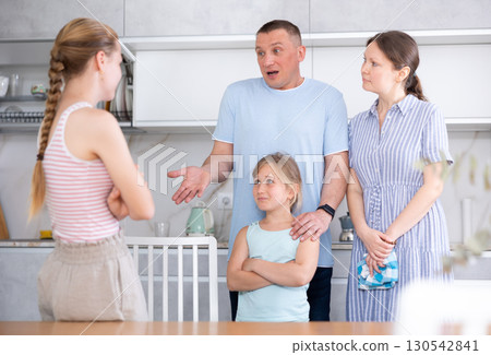 Teenage girl listening to disapproving words of father and mother Teenage girl listening to disapproving words of father and mother 130542841