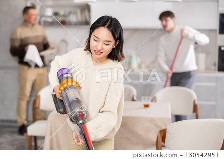Young woman vacuuming kitchen floor Young woman vacuuming kitchen floor 130542951